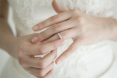 左手薬指に結婚指輪をはめる女性